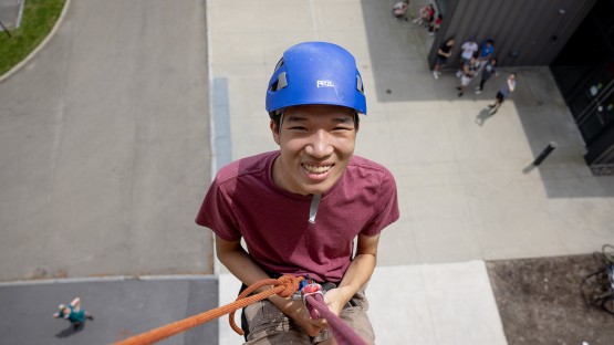 A student descends down Schoellkopf Stadium during a rappelling event for Senior Days.
