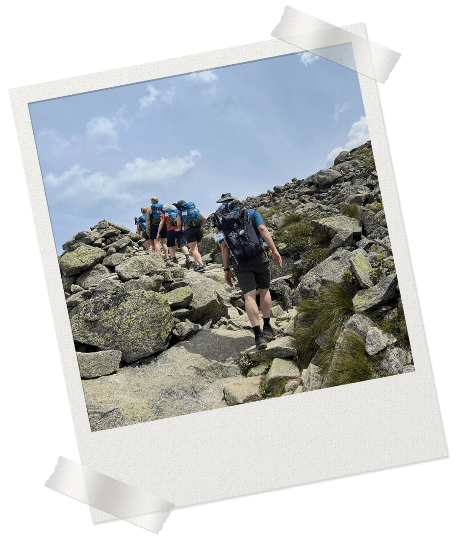 Decorative Polaroid frame containing image of hikers walking over rocky terrain in the sunlight.
