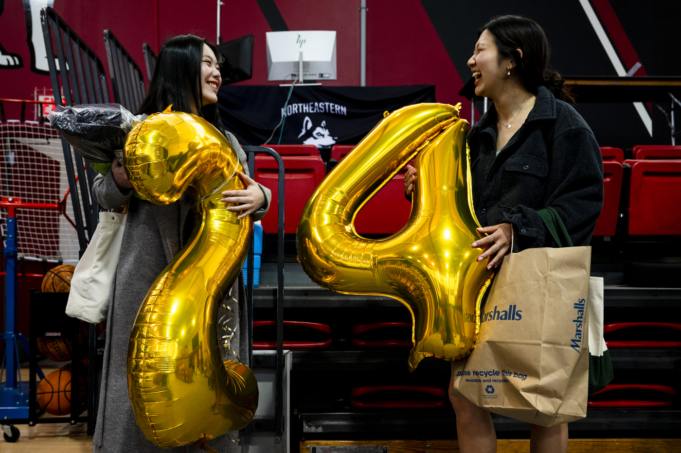 Northeastern graduates Cameron Ko and Elisa Kwon hold 2024 balloons .