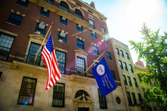 Two flags hanging on the outside of a Marymount Manhatten College building in NYC.