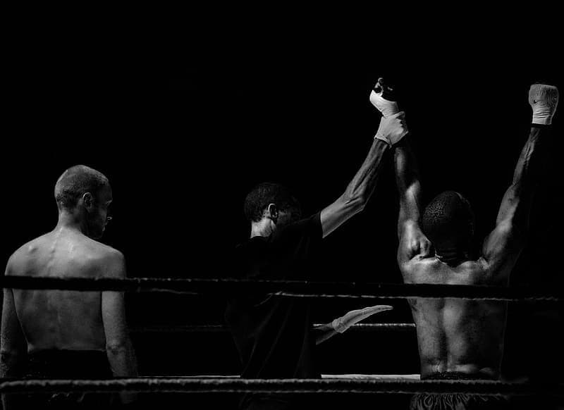 a champion's arms are raised after a boxing match