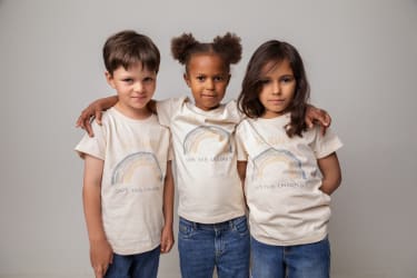 Modelbillede af tre børn i kampagne T-shirts med budskabet Be Kind