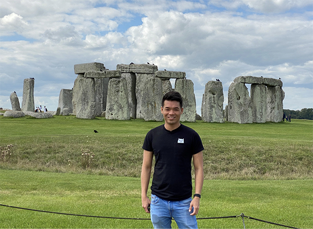"Jeffrey smiling outdoors beside Stonehenge, UK "