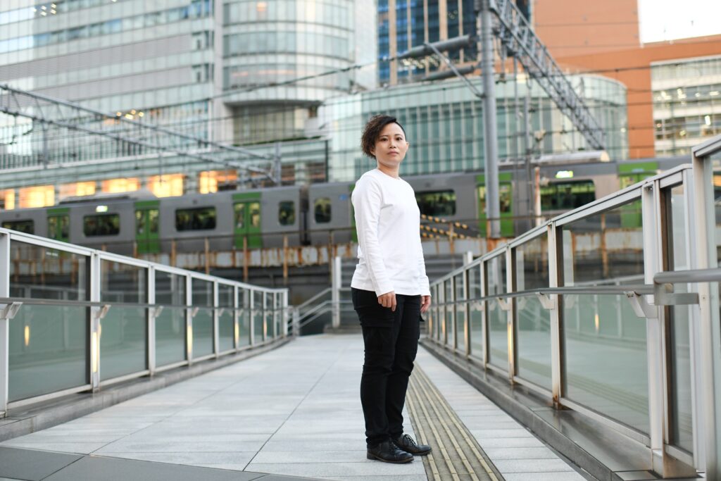 Portrait of a woman standing on a pedestrian bridge with an office building in the background