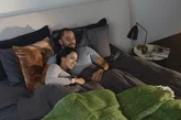 A couple wearing smartwatches while laying in bed