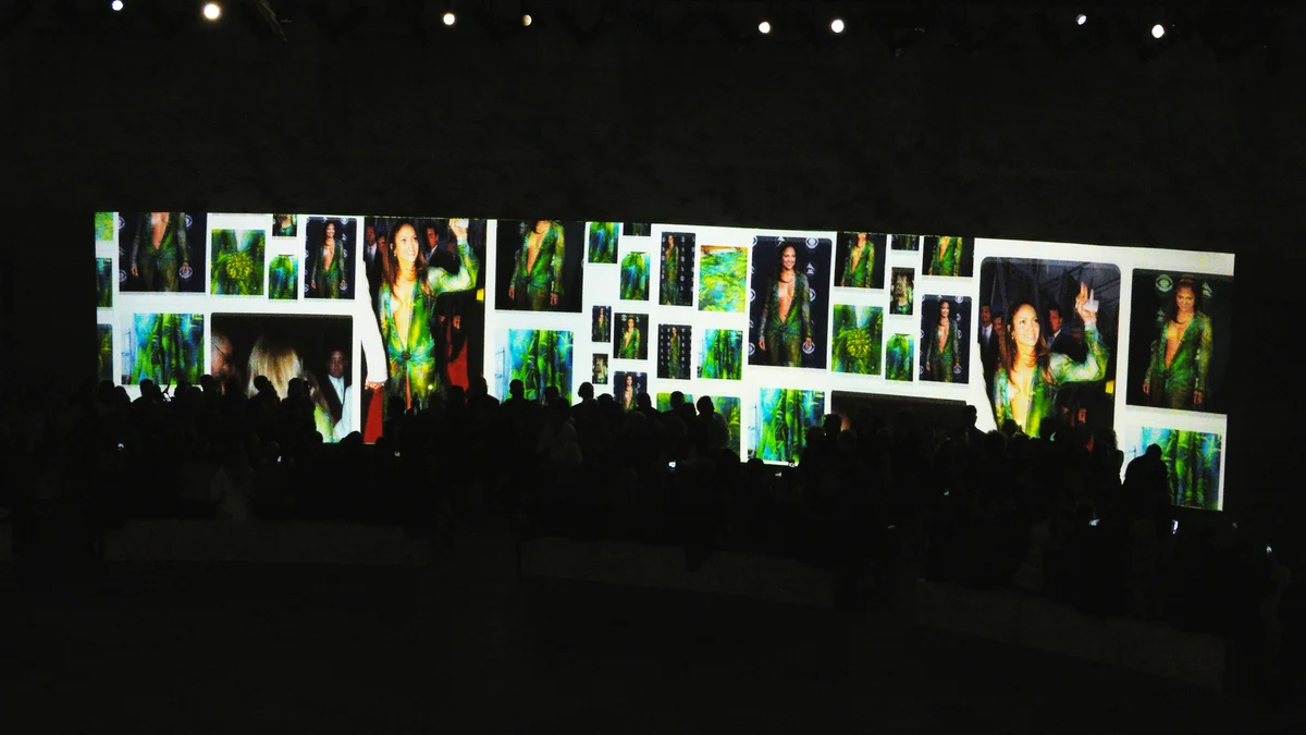 A collage of green dress images projected on a wall at Milan Fashion Week