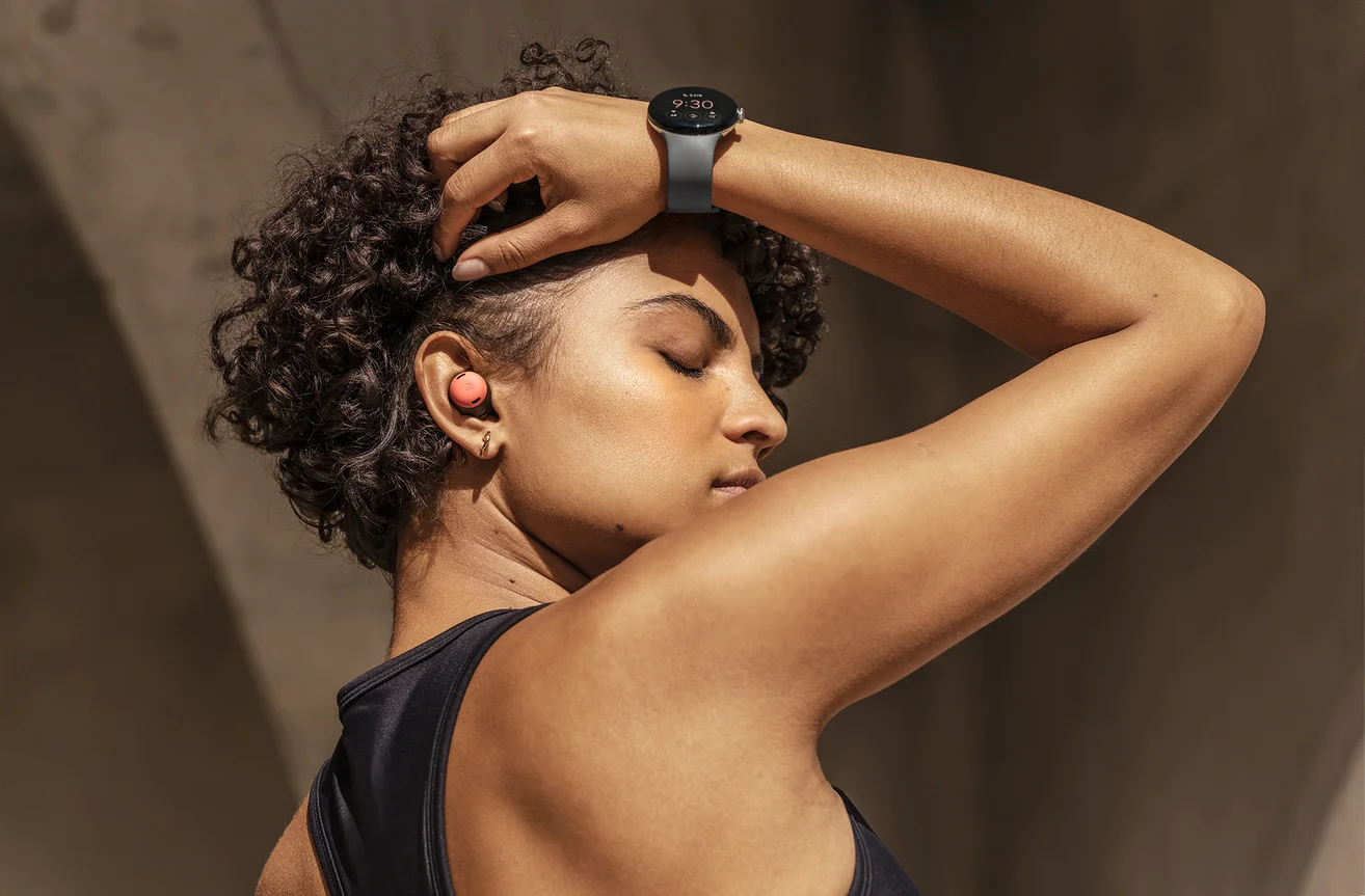 A woman in a black tank top uses Pixel Buds and a Google Pixel Watch.