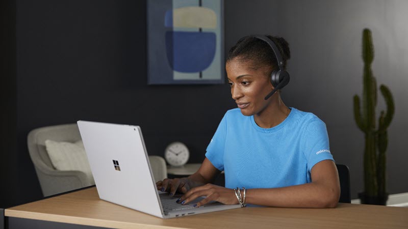 Жена носи слушалки, докато използва лаптоп
