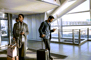 Personen auf einem Flughafen, die Ihre mobilen Geräte überprüfen.