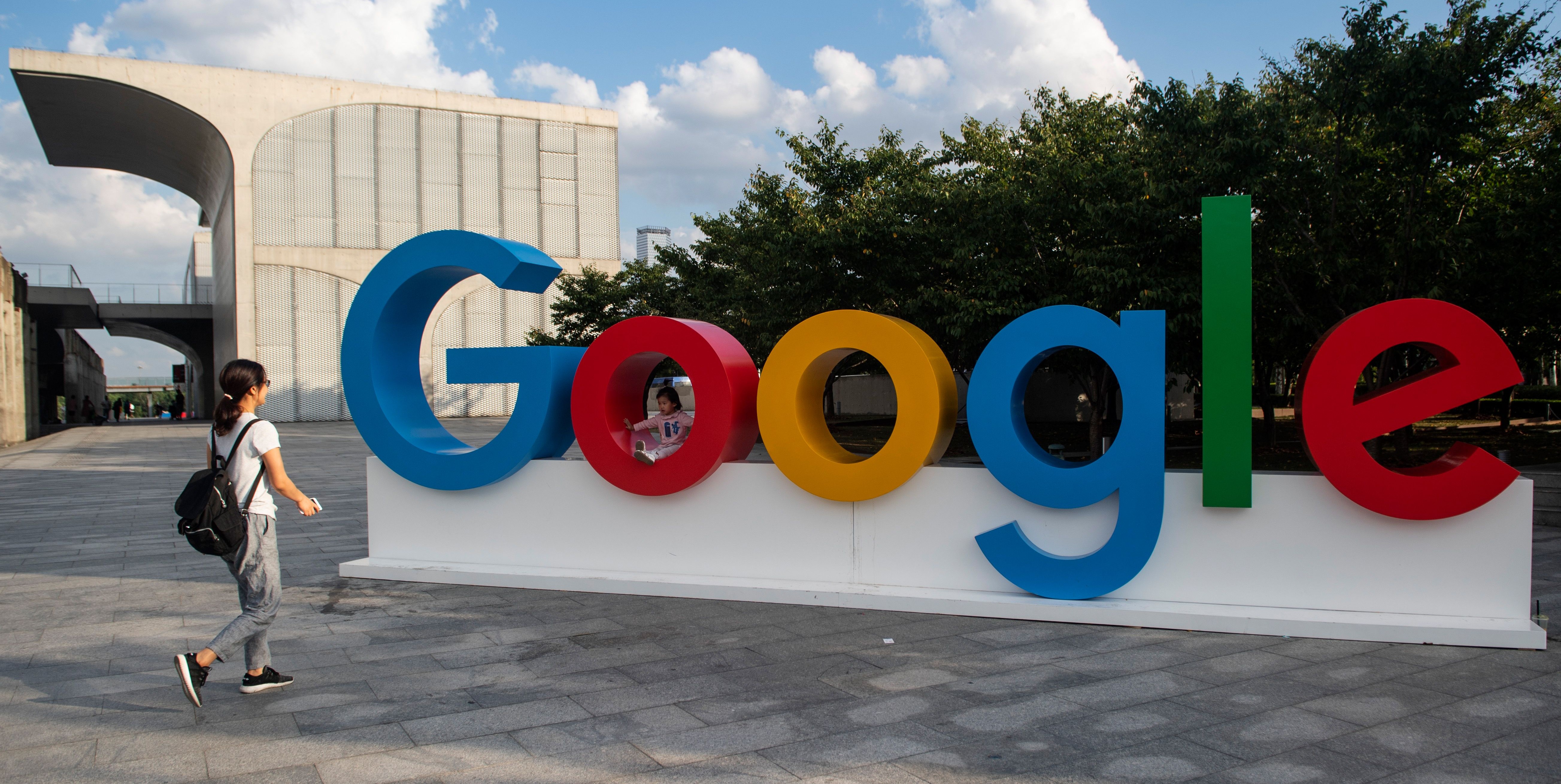 A woman and her child play on a Google sign at the World Artificial Intelligence Conference (WAIC) in Shanghai on September 26, 2018. (Photo by Johannes EISELE / AFP)        (Photo credit should read JOHANNES EISELE/AFP/Getty Images)