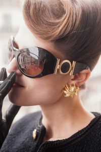 Versace sunglasses; Celine by Hedi Slimane boucle tweed jacket; Hermès gloves; Oscar de la Renta earrings.