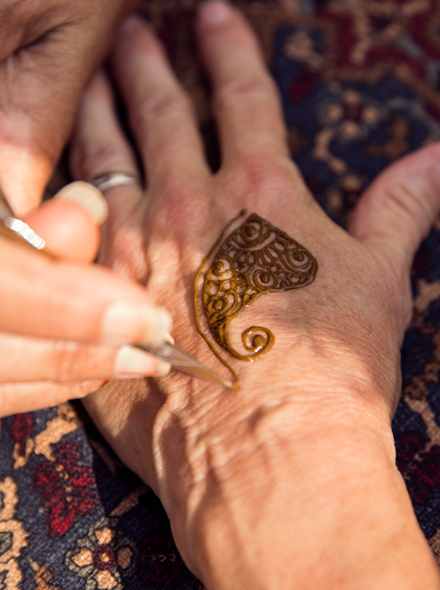 Közeli fénykép egy kézről, amint hennatetoválást készít egy másik személy kezére.
