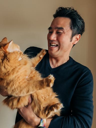 Portrékép Tetsuról, ahogy mosolyogva a kezében tartott macskájára néz