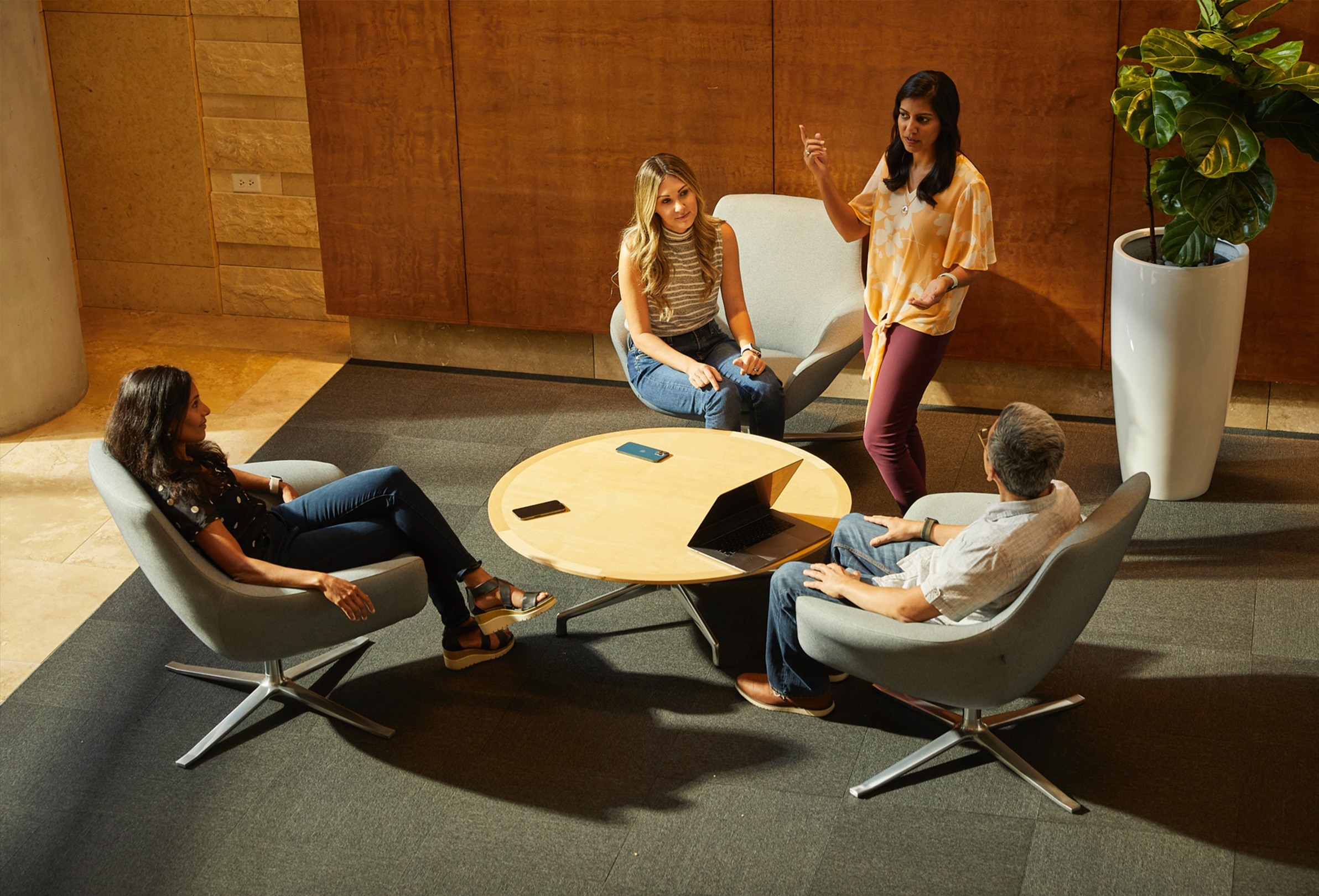 Quattro dipendenti Apple che si confrontano in uno spazio collaborativo dallo stile informale.