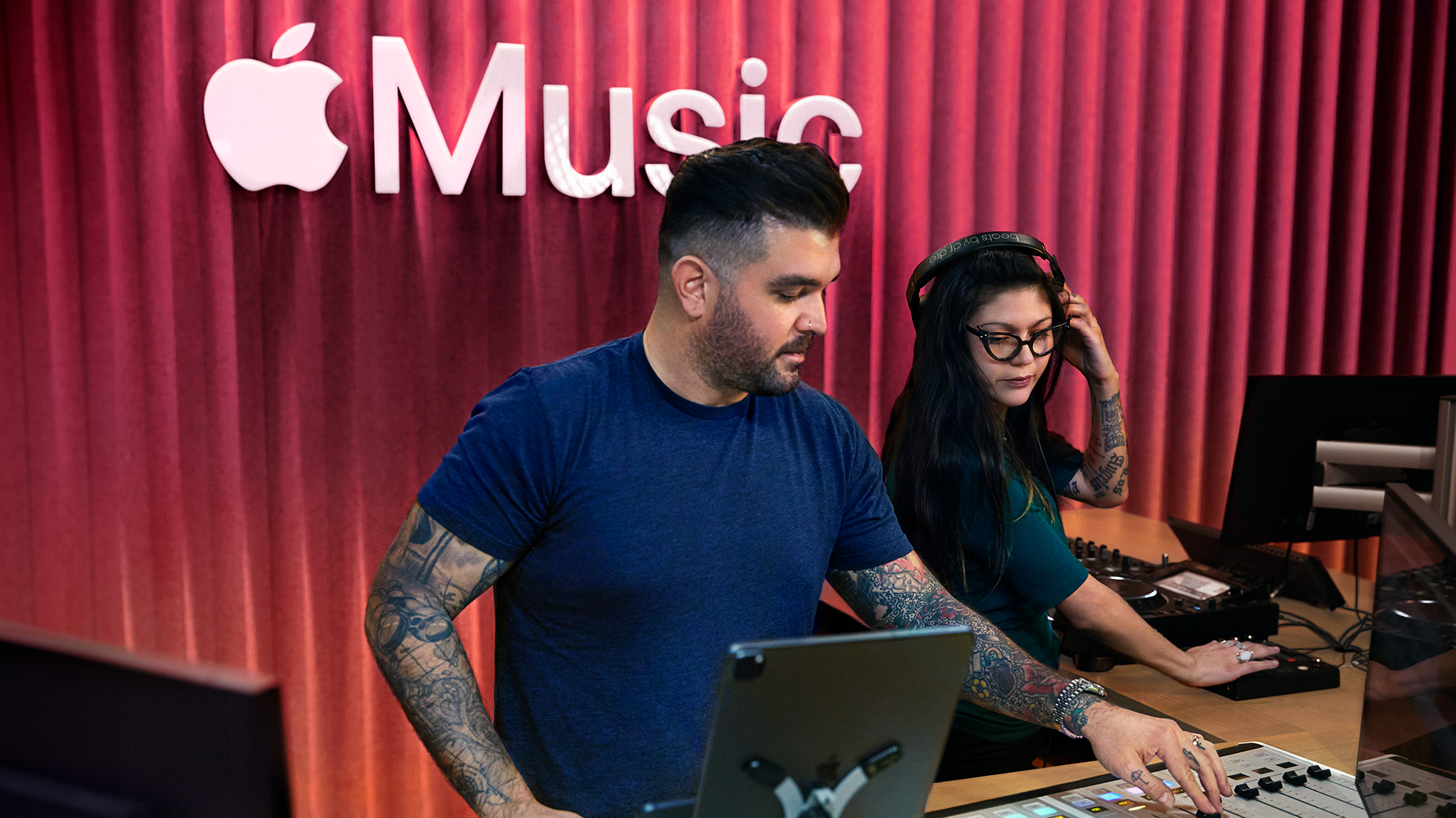 Två Apple-medarbetare använder ett ljudmixerbord i en Apple Music-studio.