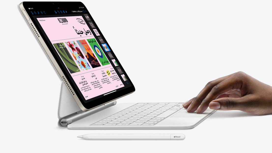 صورة جانبية لجهاز iPad Air يعرض تطبيق Keynote، ومتصل بلوحة مفاتيح ماجيك، مع يد ترتكز على لوحة التعقب، وبجانبه قلم Apple.