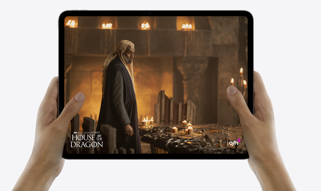 يدان تحملان جهاز iPad Pro يعرض تطبيق TV بينما يشغِّل مسلسل 'Monarch: Legacy of Monsters'.