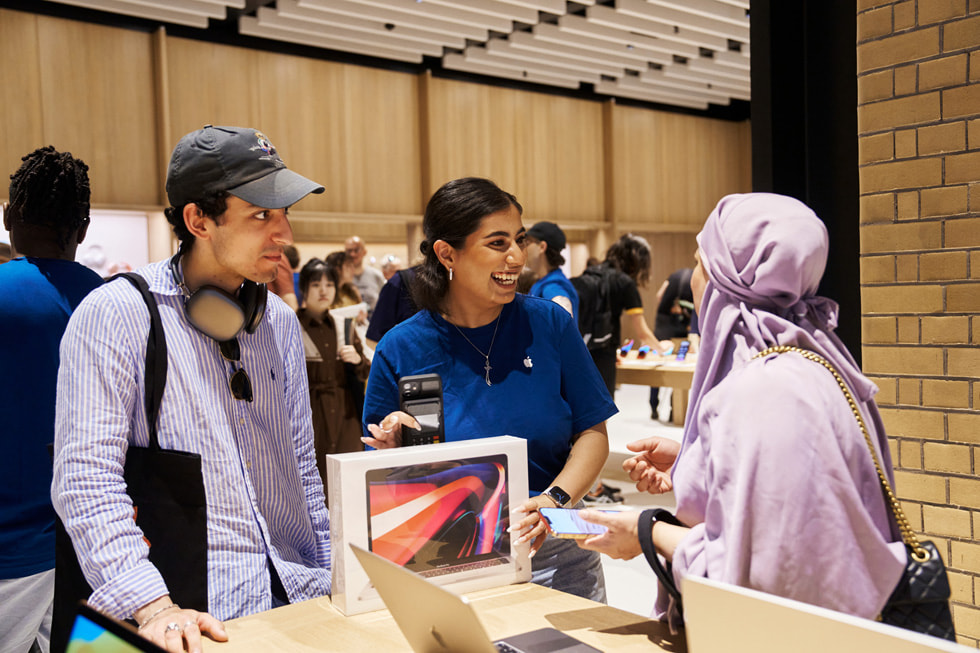 Un membre de l’équipe Apple aide une cliente à acheter son nouveau MacBook Pro.