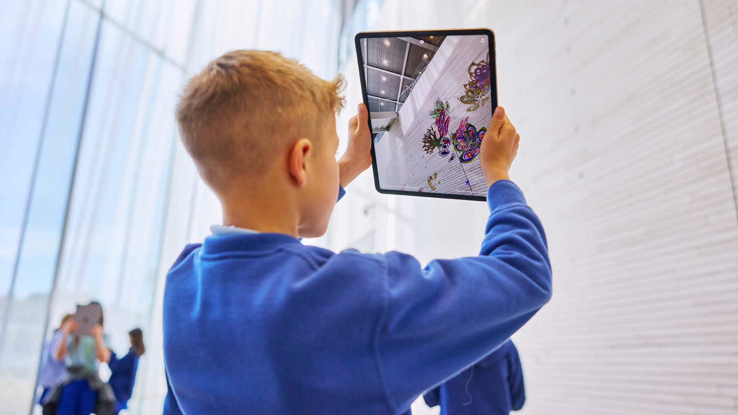Unge barn bruker Deep Field-appen på iPad Pro på en vegg.