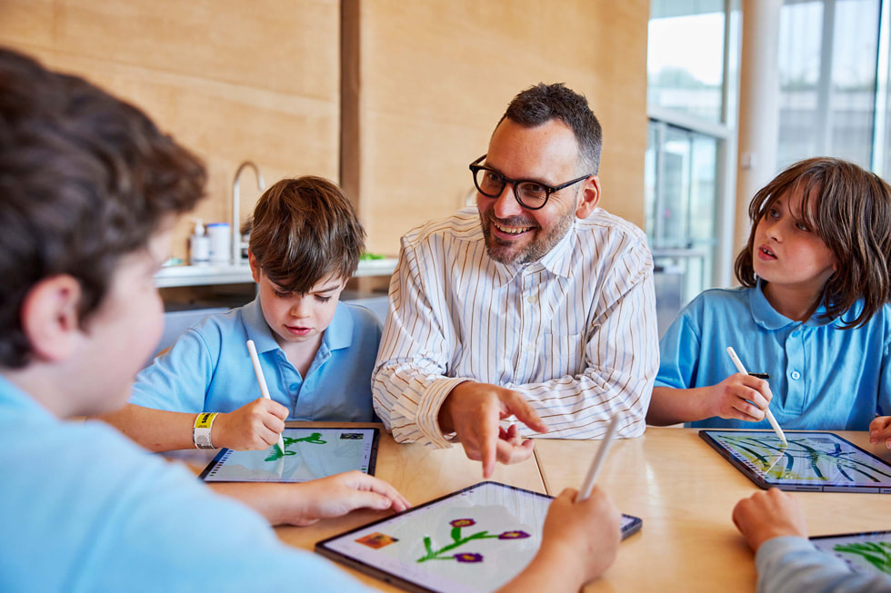 الفنان إدوارد كاتينج يجلس مع فنانين صغار يعملون باستخدام iPad Pro وقلم Apple.
