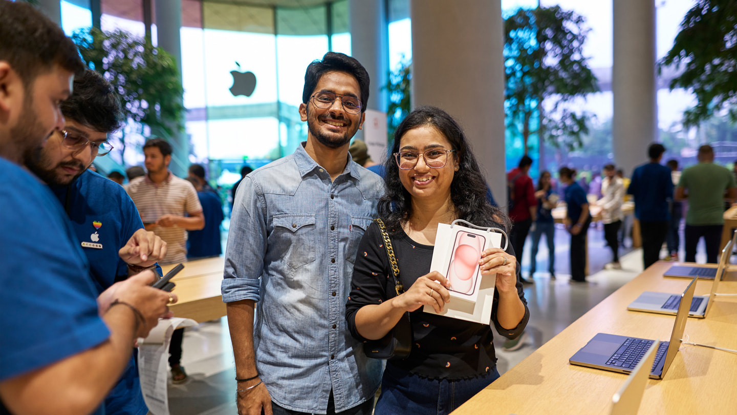 Hai khách hàng đang tạo dáng chụp ảnh bằng iPhone 15 mới mua bên trong cửa hàng Apple BKC ở Mumbai.