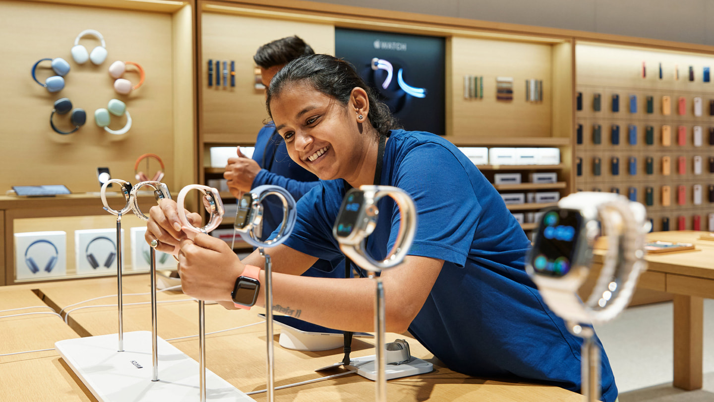 Ein Apple BKC Teammitglied richtet die neue Apple Watch Series 9 auf dem Display Table des Stores zurecht.