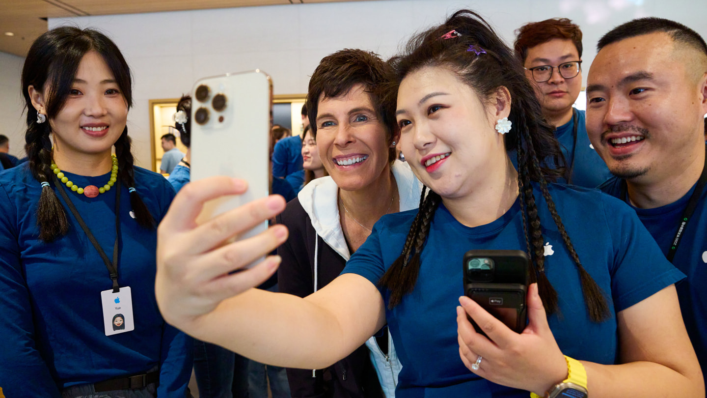 Nhân viên cửa hàng chụp ảnh selfie với Deirdre O’Brien và những nhân viên khác bằng iPhone 15 Pro màu trắng.