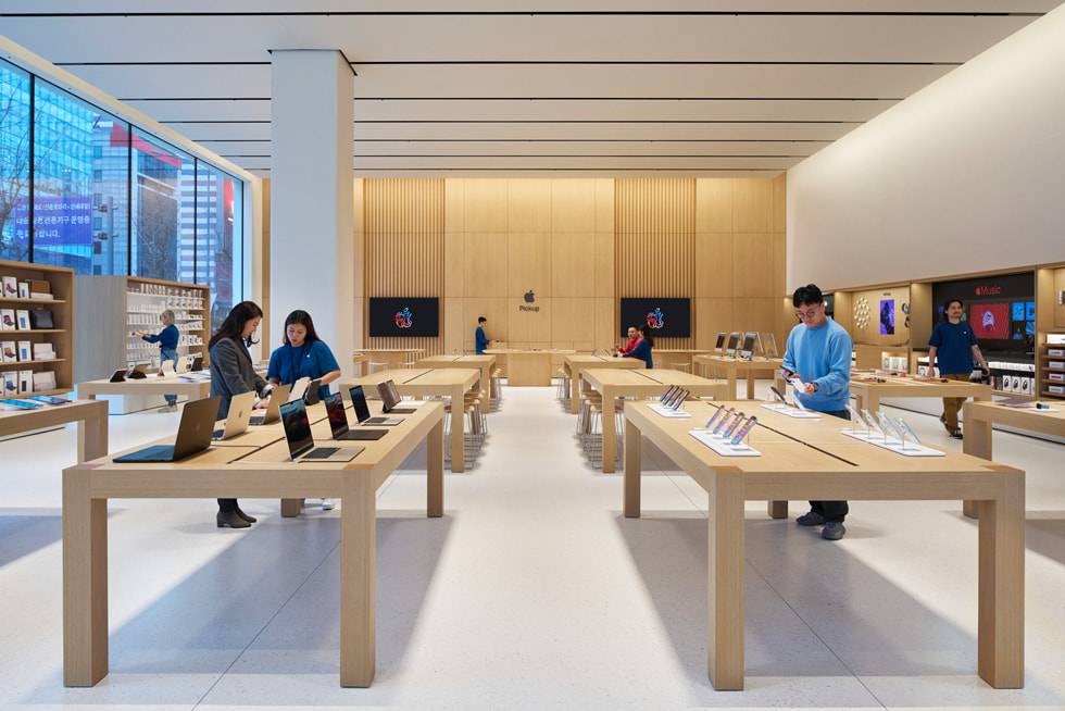 Várias mesas exibem os novos produtos Apple no interior da loja.