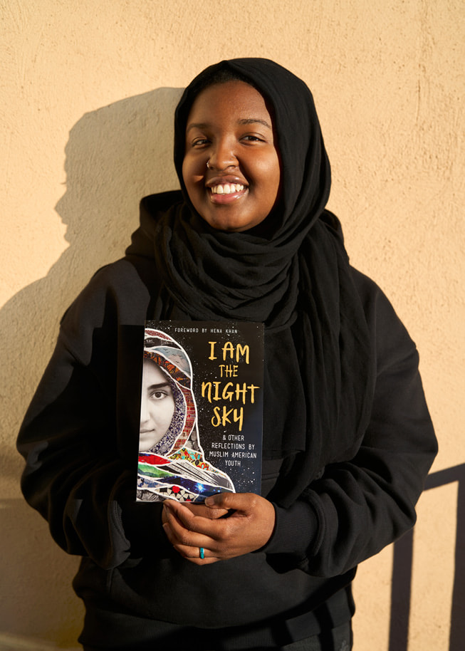 Sasa Aakil, que participa en el programa de Shout Mouse Press, posa con un ejemplar del libro *I Am the Night Sky*, del que es coautora.