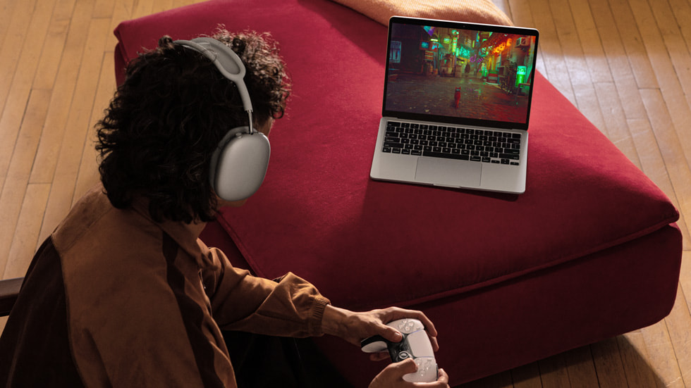 Osoba se sluchátky na uších hraje na MacBooku Air hru.