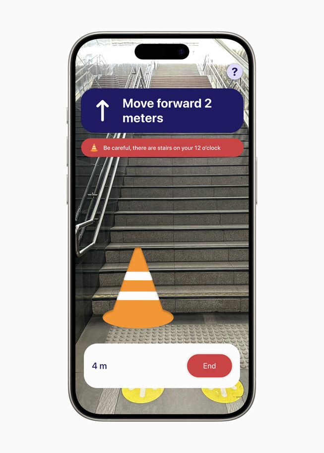 iPhone 15 Pro 上《PetaNetra》app 的螢幕提示使用者「向前移動 2 公尺」，並附有一則註釋，寫著「小心，12 點鐘方向有樓梯。」 