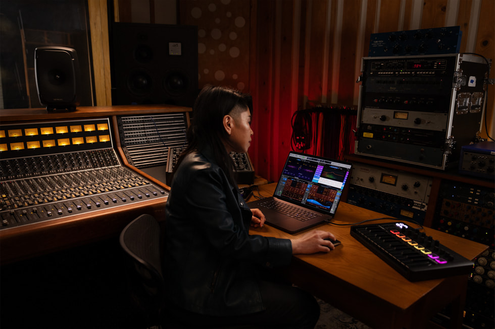 Viser en Logic Pro-bruker som jobber på MacBook Pro i et musikkstudio.