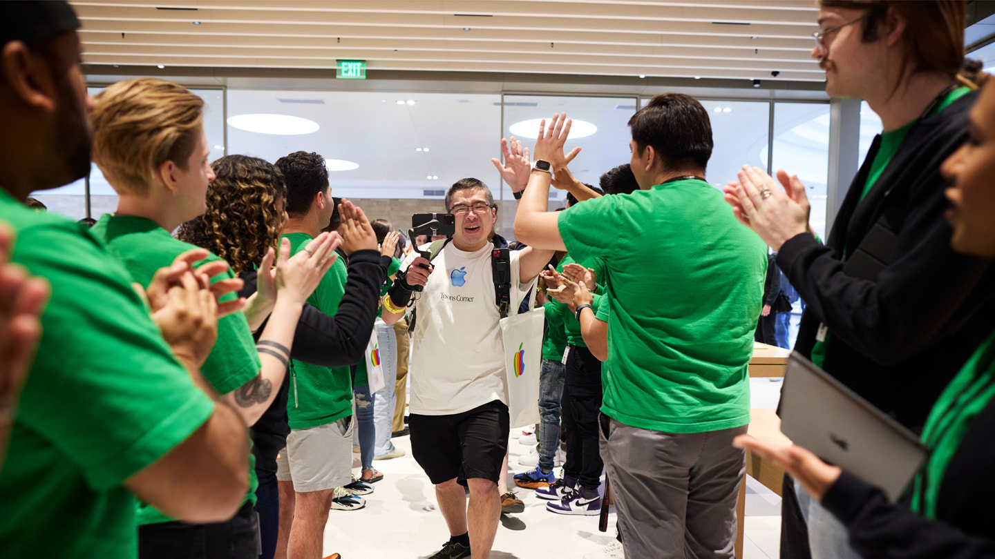 Customers are shown walking into Apple Tysons Corner while team members clap.