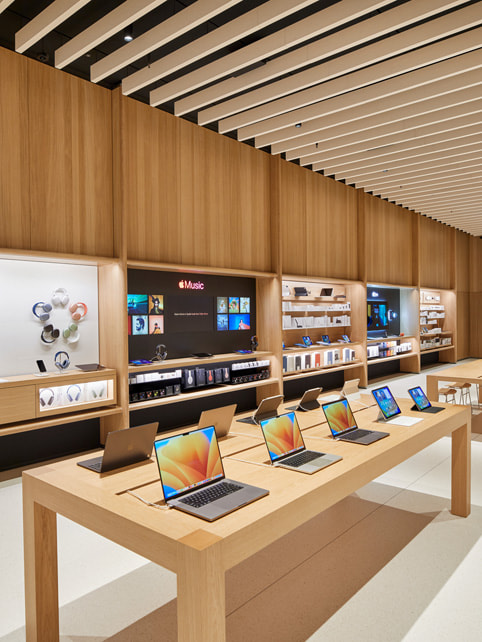 Foto da bancada do Mac e vitrine de produtos na Apple Tysons Corner.