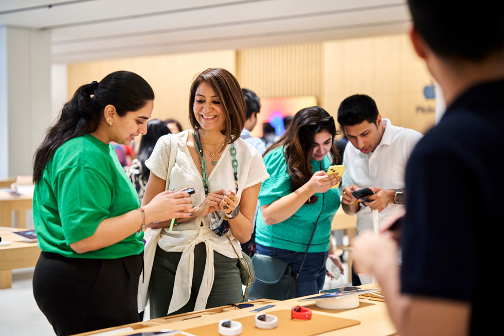 Een klant die door een medewerker wordt geholpen bij een opstelling van de nieuwste Apple Watch-modellen.