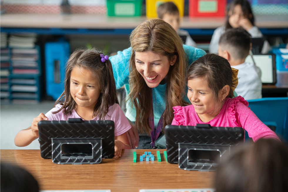 Downey Unified 學區的教師 Lindsay Barnes 在課堂上使用 iPad 與兩名一年級學生合作。