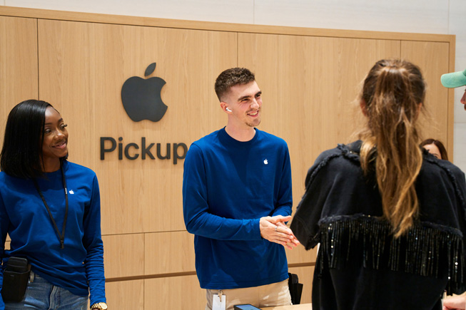 Apple 團隊成員在 Apple 零售店的 Apple 取貨區域協助顧客自取訂購的產品。