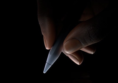 Naudotojas laiko „Apple Pencil Pro“ ties apatiniu trečdaliu tarp nykščio ir rodomojo piršto ketindamas rašyti.