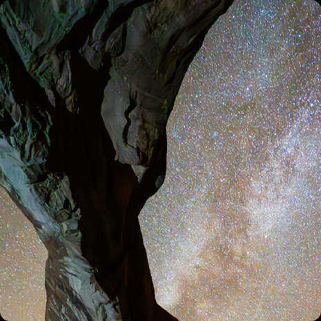 Fotogrāfija ar klinšainu veidojumu priekšā zvaigžņotām nakts debesīm