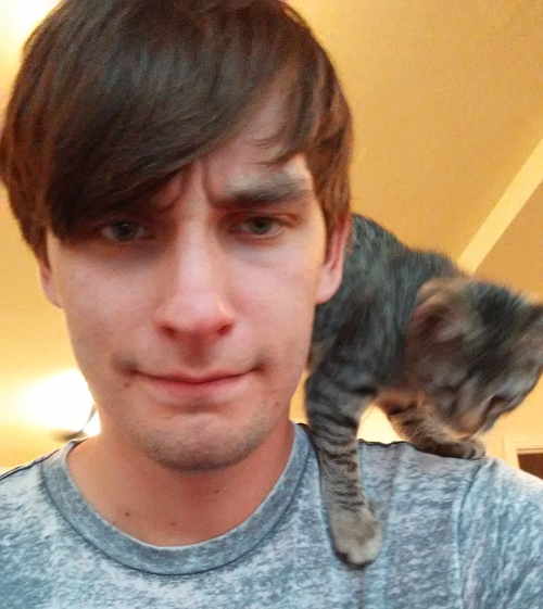 Picture of man with short brown hair and a cat on his shoulder