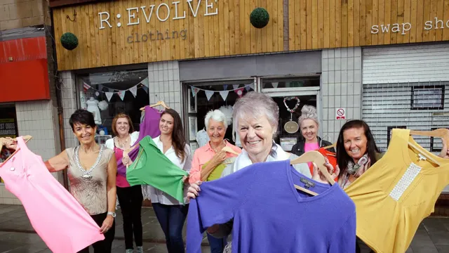 Un grupo de mujeres sonríen mientras sostienen ropa frente a una tienda R:evolve.