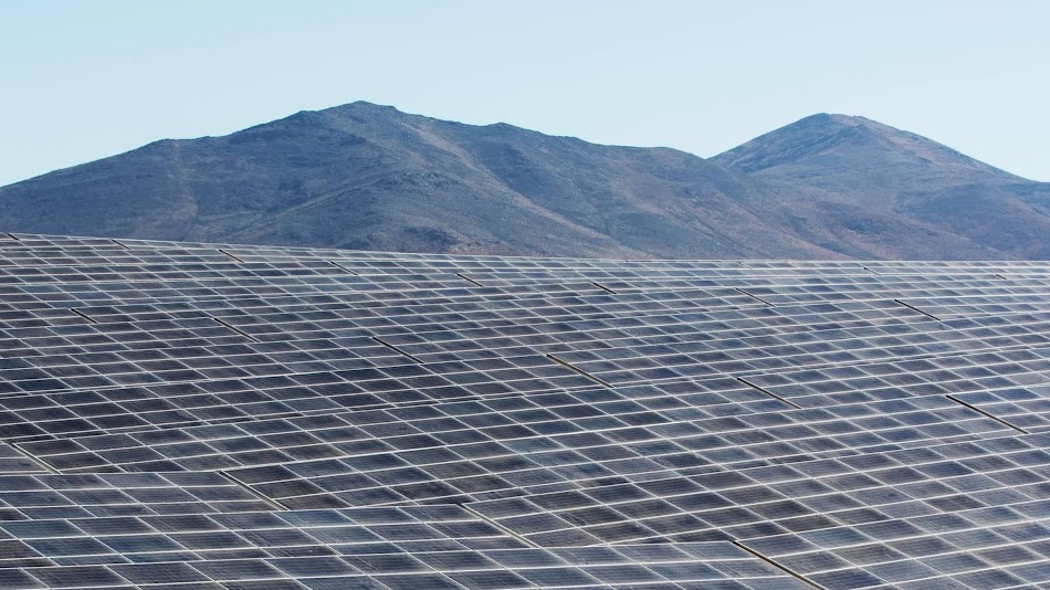 Rows of solar panels aligned in a desert landscape.