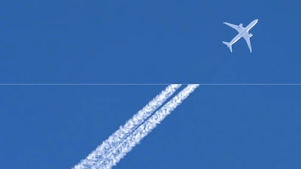 Avión en el cielo azul con estelas de condensación detrás