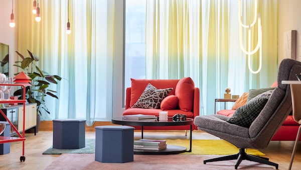 Two KJUGE pouffes with storage, a SÖDERHAMN corner section and a HAVBERG swivel armchair stand in a bright living room.