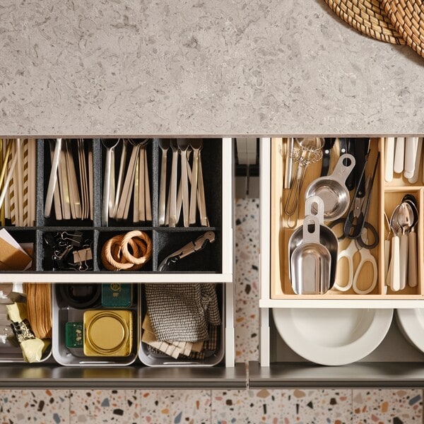 Four pulled-out MAXIMERA kitchen drawers with various items in a cutlery tray, an adjustable organiser for drawer and boxes.