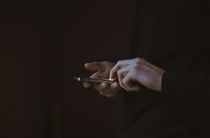 Person using smartphone, hands on black background