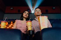 Two people in a movie theater with popcorn and soda
