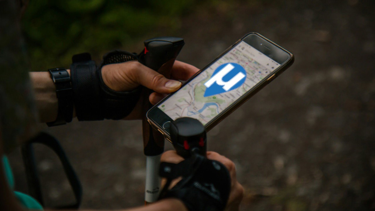 A photograph of a person looking at a digital map while trekking.