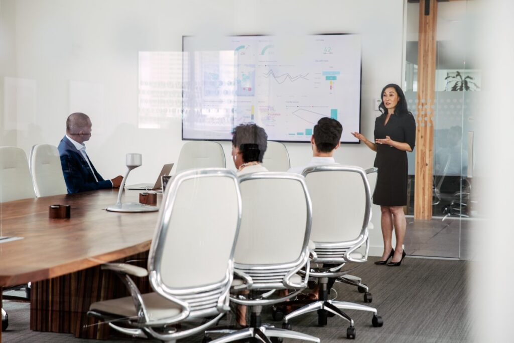 Female executive giving presentation to group in corporate office conference room.