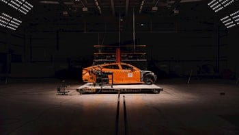 Polestar 5 sits in the middle of crash test facility surrounded by lights